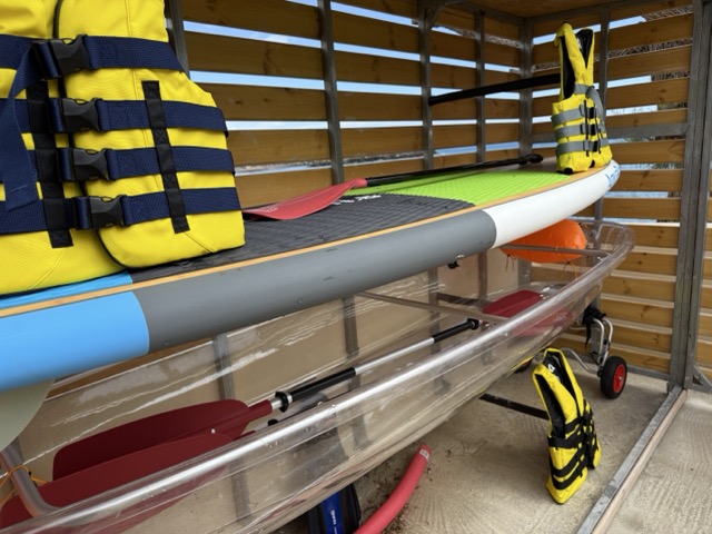 Water sports equipment storage with colorful SUP boards, kayaks, and life jackets