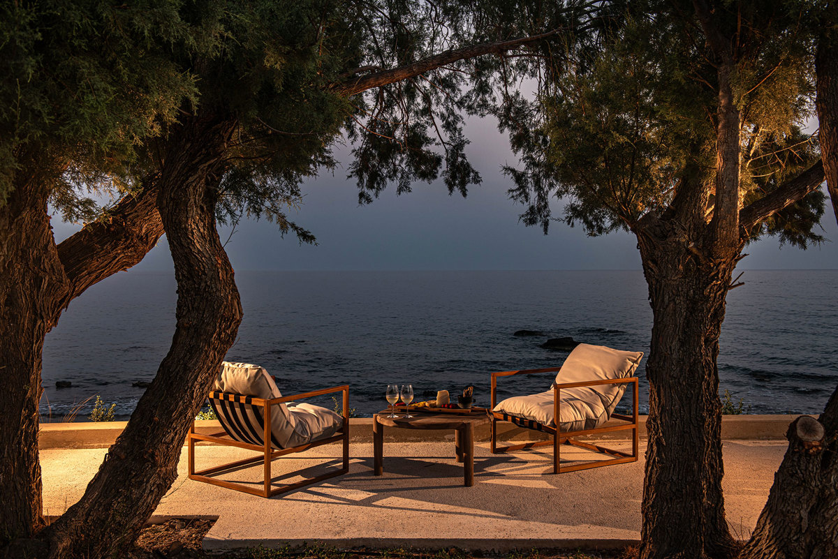 Evening seating area by the sea under olive trees